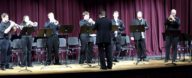 Luis Engelke conducting a trumpet ensemble on stage
