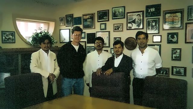 Luis Engelke with four colleagues in a room lined with framed photographs