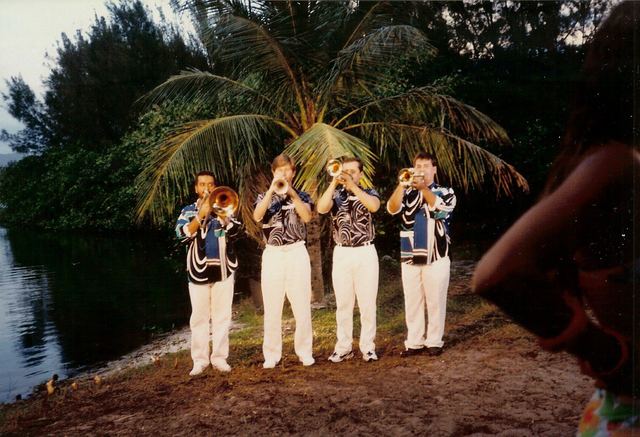 Four trumpeters in matching shirts on a beach at night