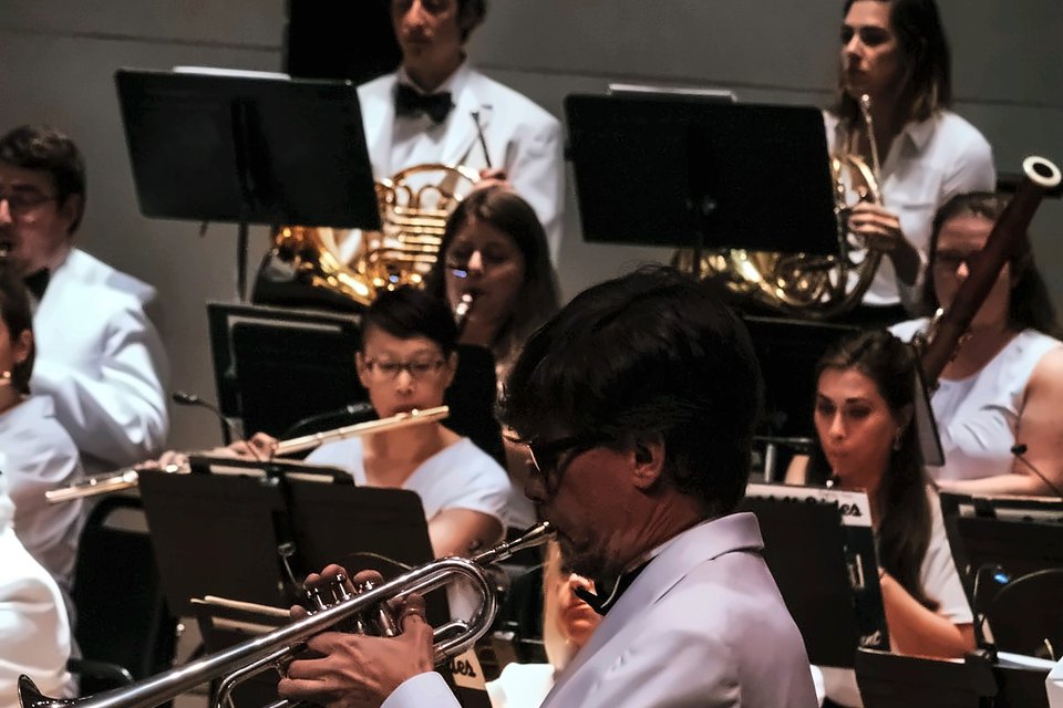 Luis Engelke performing as trumpet soloist in a white jacket with an orchestra