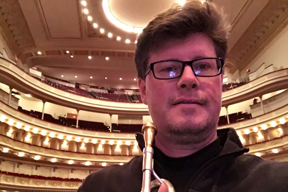 Luis Engelke holding his trumpet on the Carnegie Hall stage, with the balconies behind him
