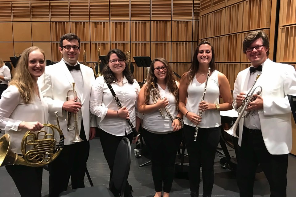 Luis Engelke with five Towson University student interns holding their instruments on stage