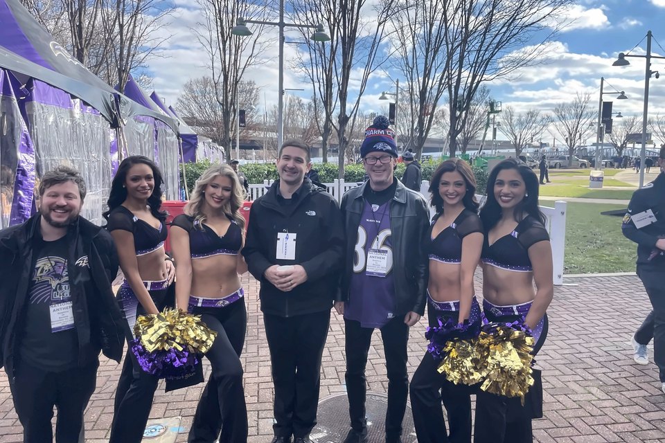 Luis Engelke with two colleagues and four Ravens cheerleaders outside the stadium